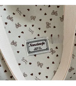 Detail of waffle fabric tote with heart bow prints and branded rectangular woven label