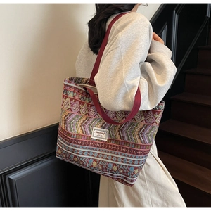 Detailed texture of ethnic woven tote bag with colorful geometric patterns and red handles