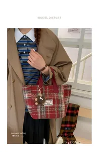 Detail of retro plaid wool tote bag featuring a cute plush monster charm and brand tag