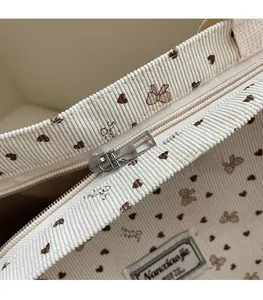 Detail of corduroy tote bag with brown heart pattern and smooth silver metal zipper