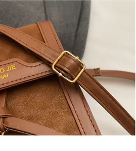 Macro detail of brown suede crossbody bag with adjustable strap and golden hardware