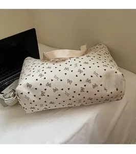 Detailed shot of beige canvas tote bag with heart patterns on a bed with a laptop