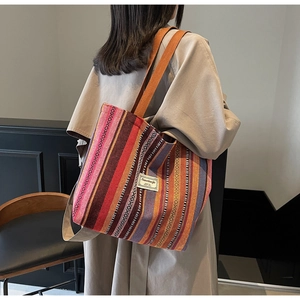 Detail of bohemian striped canvas tote bag with brown straps worn on a beige trench coat
