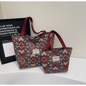 Détail de sacs cabas ethniques tissés en deux tailles avec poignées rouges en sangle