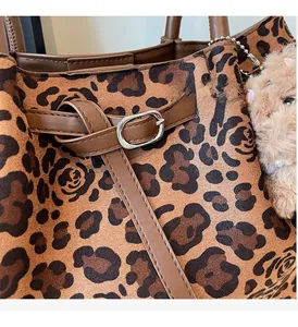 Detail of leopard print tote bag featuring metallic hardware and faux fur bear charm