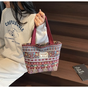 Detail of vintage ethnic style woven handbag with colorful floral patterns on wooden stairs