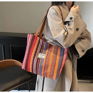 Detailed close-up of large capacity colorful striped canvas tote bag on a model