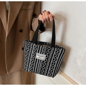 Close-up of geometric ethnic woven tote bag with contrast handle and logo patch detail