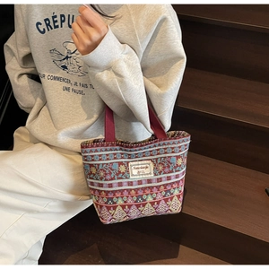 Detailed shot of ethnic style jacquard tote bag with geometric patterns and red handles