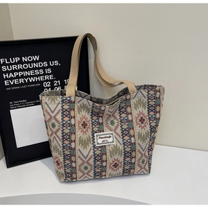 Détail d'un sac cabas tissé ethnique montrant des motifs géométriques et une sangle