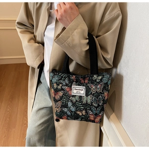 Detailed close-up of floral butterfly jacquard fabric and brand label on a tote bag