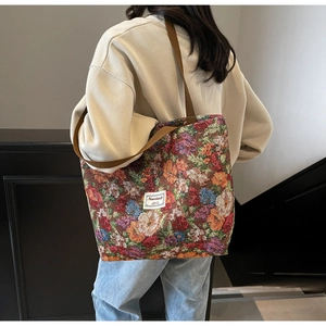 Détail du sac cabas jacquard floral vintage avec large bandoulière marron sur un modèle