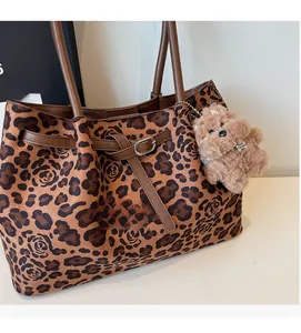 Close-up of leopard and rose print tote bag featuring plush suede and brown leather straps