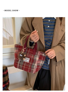 Detail of red plaid wool tote bag featuring a cute plush monster charm and brand tag