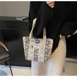 Close-up of geometric ethnic woven canvas tote bag with colorful patterns and beige handles