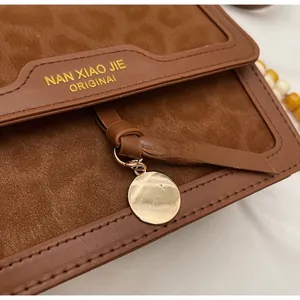Détail du sac léopard vintage avec finition en daim marron et pendentif doré rond
