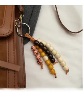 Close-up of ethnic leopard print wood bead bag charm with gold metal clasp on leather bag