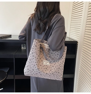 Détail du sac cabas en velours côtelé gris avec motifs de cœurs noirs et bandoulière