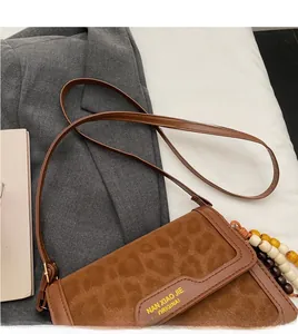 Détail du sac à bandoulière léopard avec perles en bois et logo de marque