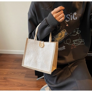 Linen bento bag detail with wood button closure and textured cream fabric panels