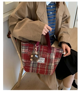Detail of red-brown checkered wool tote bag with soft plush charm and sturdy handles
