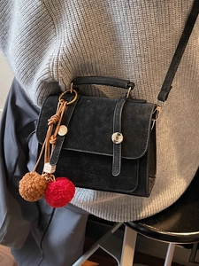 Borsa a tracolla nera stile British con ciondolo peluche su maglione grigio