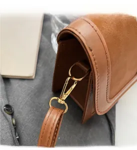 Gros plan sur le sac en cuir marron avec fermoir mousqueton en métal doré poli