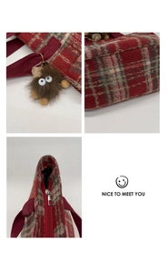 Detail of red plaid tote bag with zip closure and cute brown plush monster charm