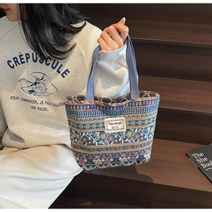 Close-up of ethnic floral pattern on a blue jacquard canvas tote bag with woven handles