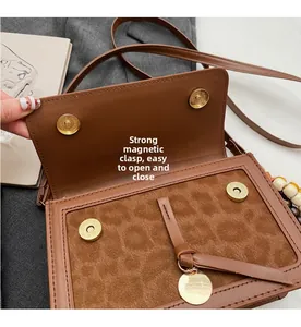 Détail du sac bandoulière léopard marron avec boucles magnétiques et texture cuir suédé