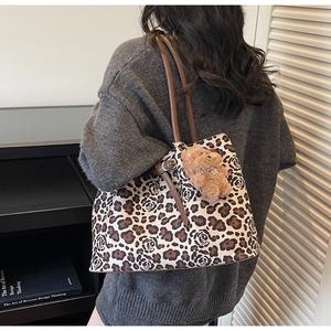 Detail of leopard and rose print tote bag with adjustable brown strap and plush bear charm