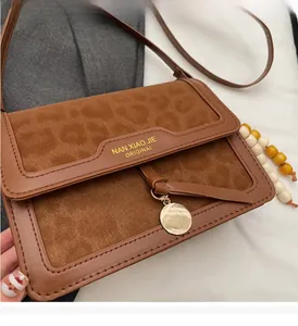 Détail de la texture suédine léopard et du cuir marron avec pendentif doré chic