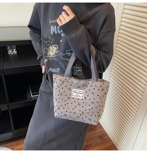 Gros plan du sac cabas en velours côtelé gris avec motifs de cœurs et de nœuds noirs