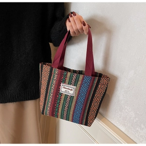 Detailed close-up of ethnic style woven tote bag with colorful stripes and fabric label