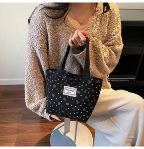Détail du sac cabas en velours côtelé noir avec motifs de cœurs et nœuds blancs