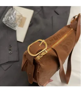 Gros plan sur la boucle dorée et la fermeture éclair d'un sac à bandoulière en daim