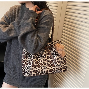 Detail of leopard and rose print tote bag with brown leather strap and plush bear charm