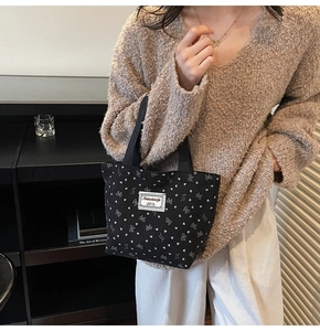 Détail d'un sac à main en velours noir avec motifs nœuds blancs et étiquette tissée