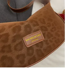 Gros plan du tissu à imprimé léopard mat et étiquette logo sur le sac à bandoulière brun