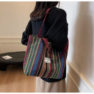 Detailed close-up of colorful ethnic woven tote bag with geometric stripes and red straps