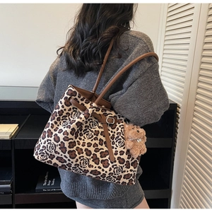 Detail of leopard and rose print canvas tote bag with brown leather strap and bear charm