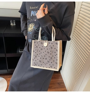 Détail du sac en lin avec imprimé cœur, nœud noir et fermeture par bouton blanc
