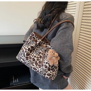 Detail of leopard and rose floral print tote bag with brown leather straps and bear charm