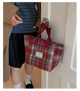 Close-up of red plaid wool tote bag hanging on a white wooden door handle