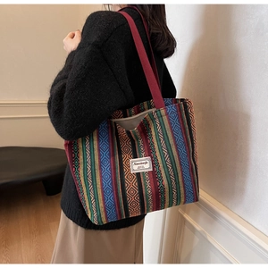 Ethnic striped canvas tote bag with brand label shown on shoulder in a lifestyle setting