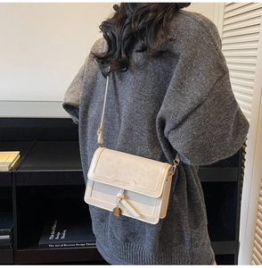 Gros plan du sac à rabat léopard blanc cassé avec pendentif en métal et détails du logo