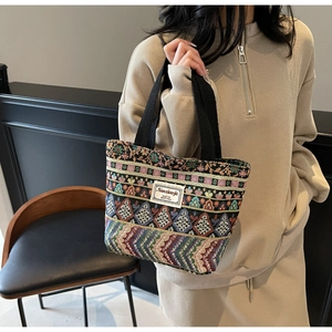 Detail of colorful ethnic jacquard tote bag with woven texture and black handles