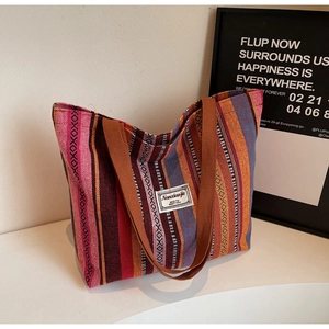 Detail of colorful ethnic stripe tote bag showing woven fabric and durable brown handles
