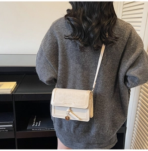 Détail du sac bandoulière beige crème avec gaufrage léopard et pendentif doré sur mannequin