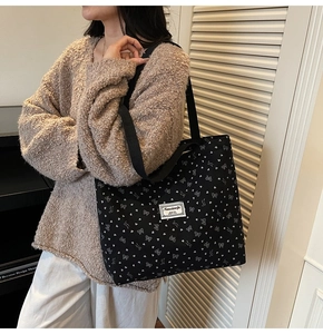 Détail d'un grand sac fourre-tout en toile avec motifs de cœurs et nœuds blancs sur noir